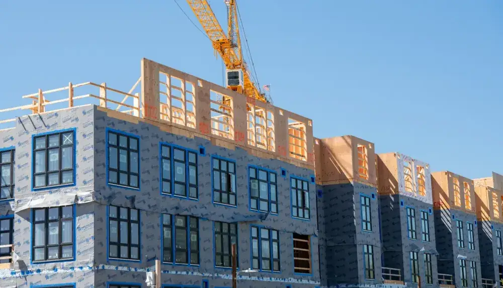 Prédio residencial em construção com guindaste sob céu azul