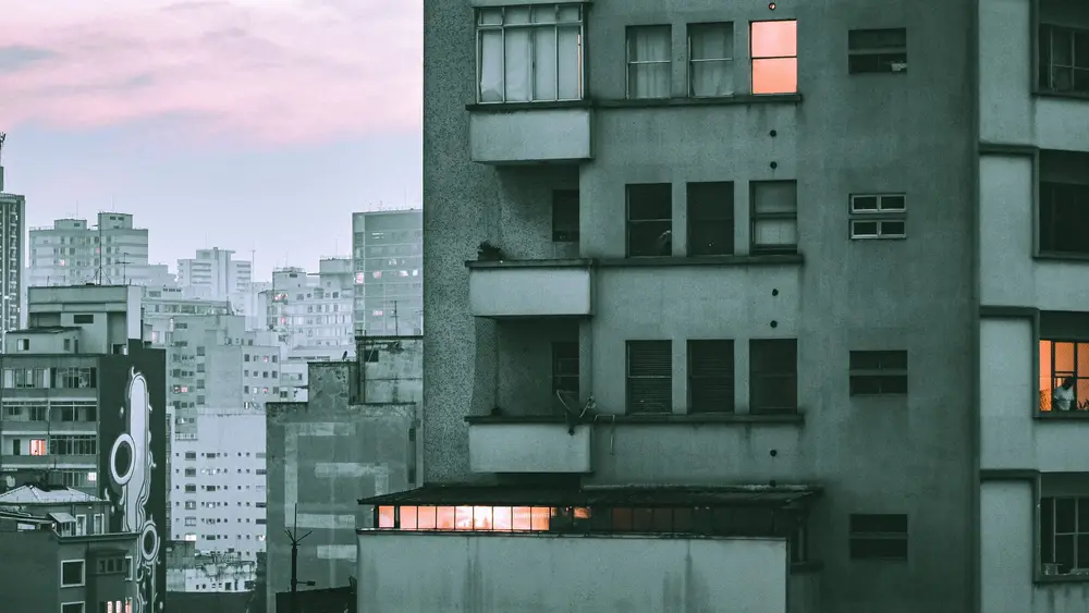 Prédios residenciais em um bairro de São Paulo no fim da tarde, com janelas acesas