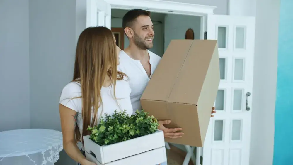 Casal recebendo as chaves do primeiro apartamento na porta de entrada do imóvel